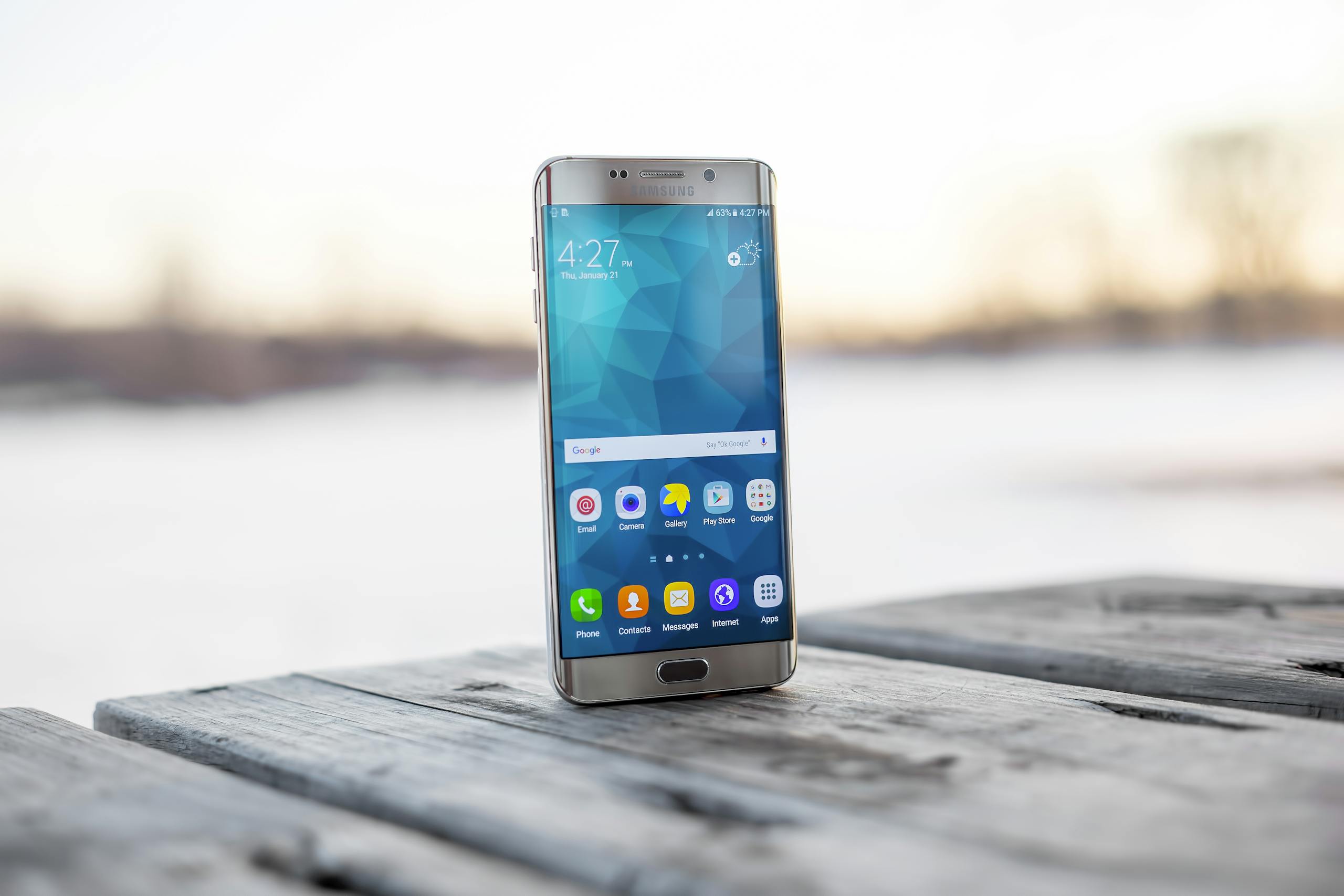 Samsung smartphone placed on a wooden surface outdoors during sunset.